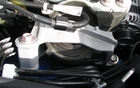 En plein centre de la photo, un support moteur en acier blanc de bonne dimension. Il est isolé du moteur par un anneau de caoutchouc afin de diminuer les vibrations.